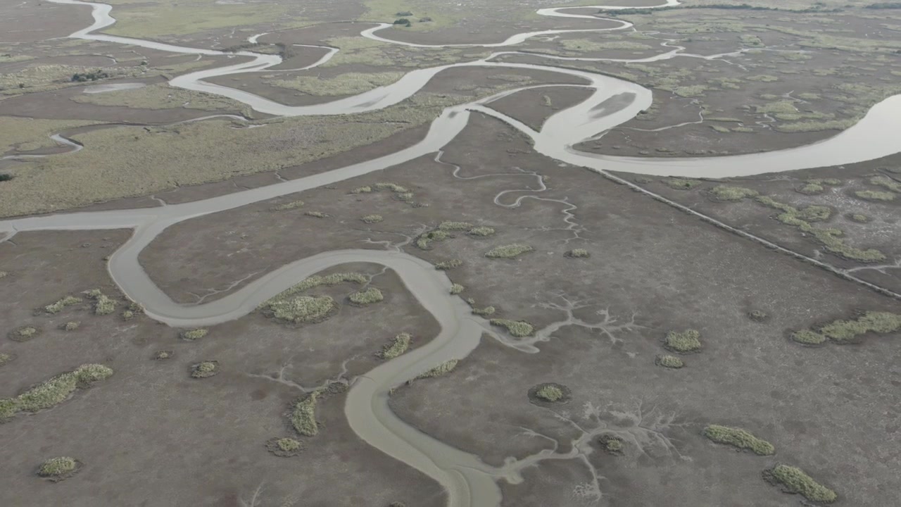 Drone slowly pulls back above winding tidal channels and expansive coastal wetlands, revealing the intricate network of waterways across Campos del Tuyú, Buenos Aires Province.