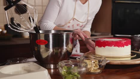 woman decorating a layered cake with red icing