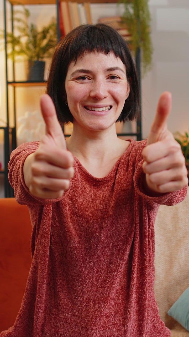 Donna caucasica entusiasta che guarda la fotocamera con approvazione, mostrando il pollice in su come segno di feedback positivo