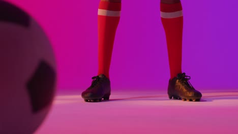 African-american-male-soccer-player-with-football-over-neon-pink-lighting