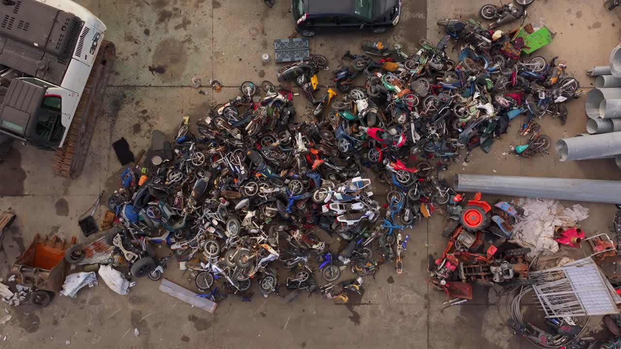 Inquadratura aerea di un centro di riciclaggio che processa cumuli di rifiuti metallici
