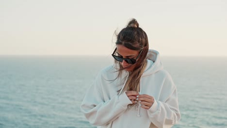 slow motion shot of a beautiful female playing with hair with the ocean behind