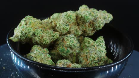 capullos de marihuana secos verdes cierran la toma conceptual, montón de plantas de marihuana secas, cepas de tricomas naranjas, en un pequeño grito negro brillante, en un soporte giratorio, luces de estudio, cámara lenta, video 2 de 4k