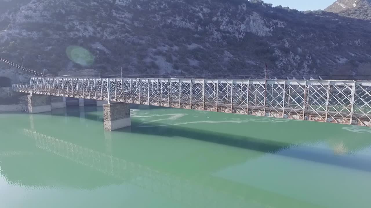 호수 위의 오래된 금속 구조 다리에서 운전하는 스테이션 왜건 유형 자동차, 공중 궤도