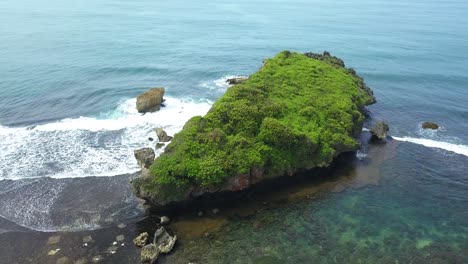Drohnenansicht-Eines-Riesigen-Korallenfelsens-Mit-Ansammlungen-Kleiner-Felsen,-Die-Von-Der-Welle-Am-Tropischen-Strand-Zerquetscht-Werden