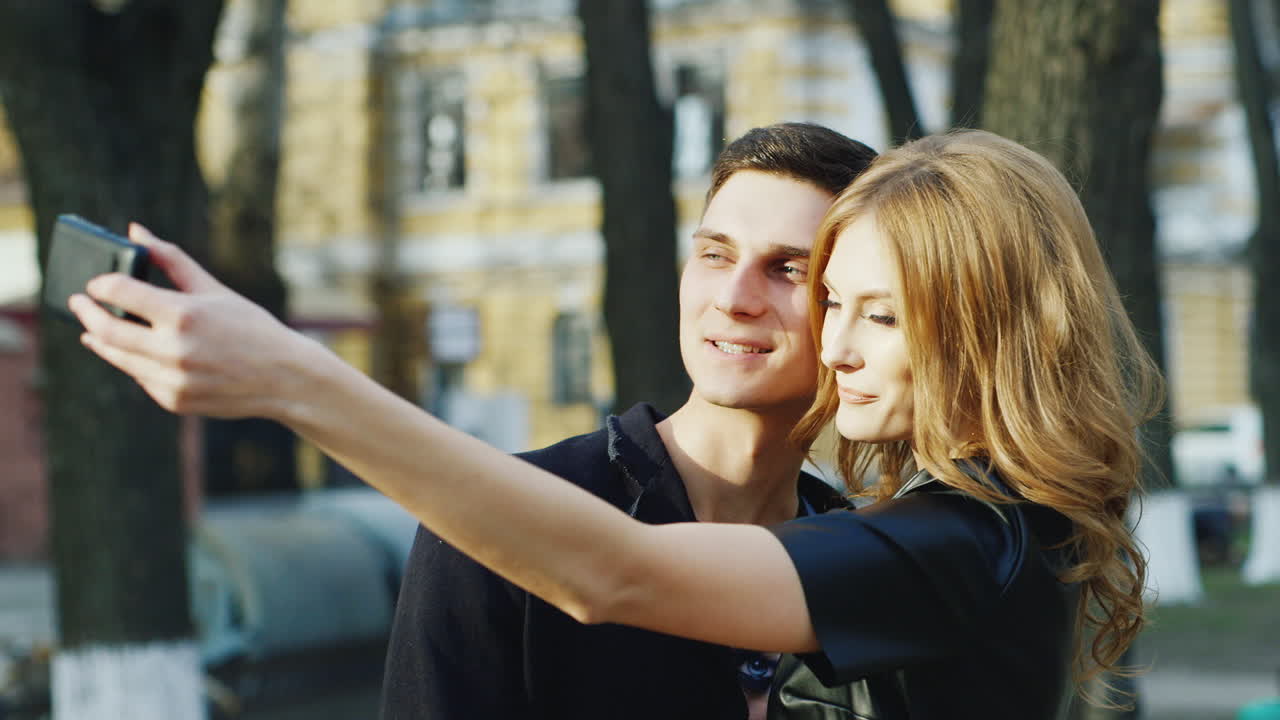 парень и девушка делают селфи в городе hd видео