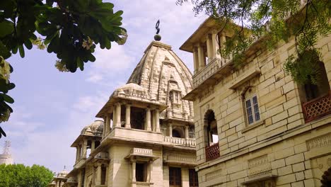 4k tilt-up video of kirti mandir temple in vadodara, gujarat, india. the shot showcases ornate heritage architecture against partly cloudy sky, framed by lush green trees