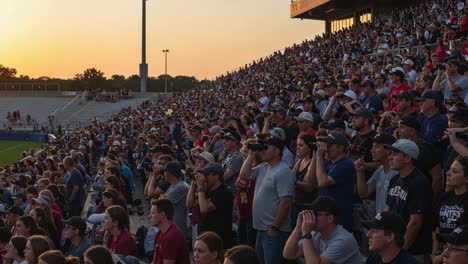a thrilling sunset scene captured in a crowded stadium, spectators engrossed in the event with anticipation, enjoying the atmosphere together as day turns to night
