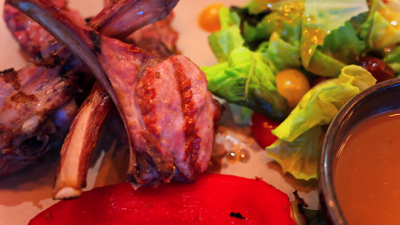 Close up of lamb chops with sauce and a side salad on a plate at a restaurant
