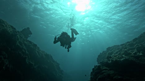 cinematic underwater shot of a scuba diver couple against the sunlight in slow motion, 4k, 120fps, slomo