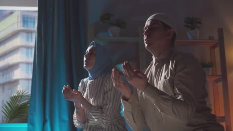 muslim man and woman in hijab pray at home close up