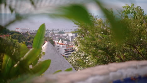 glimpse of the town and ocean view through the foliage on a hiking trail above the tropical city