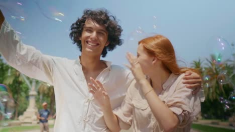 Portrait-of-love-couple-catching-soap-bubbles.-Romantic-man-and-woman-having-fun