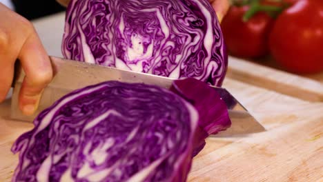 slicing fresh cabbage with tomatoes in background