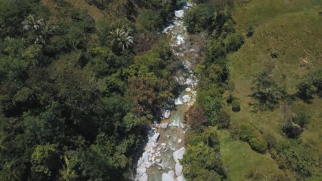 drone vista aérea de pájaro de un río que fluye con agua y rocas en un bosque en colombia