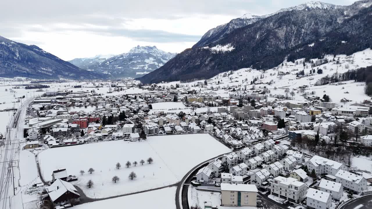 tomada aérea amplia que muestra un paisaje cubierto de nieve y casas cubiertas de nieve en el pueblo suizo llamado reichenburg