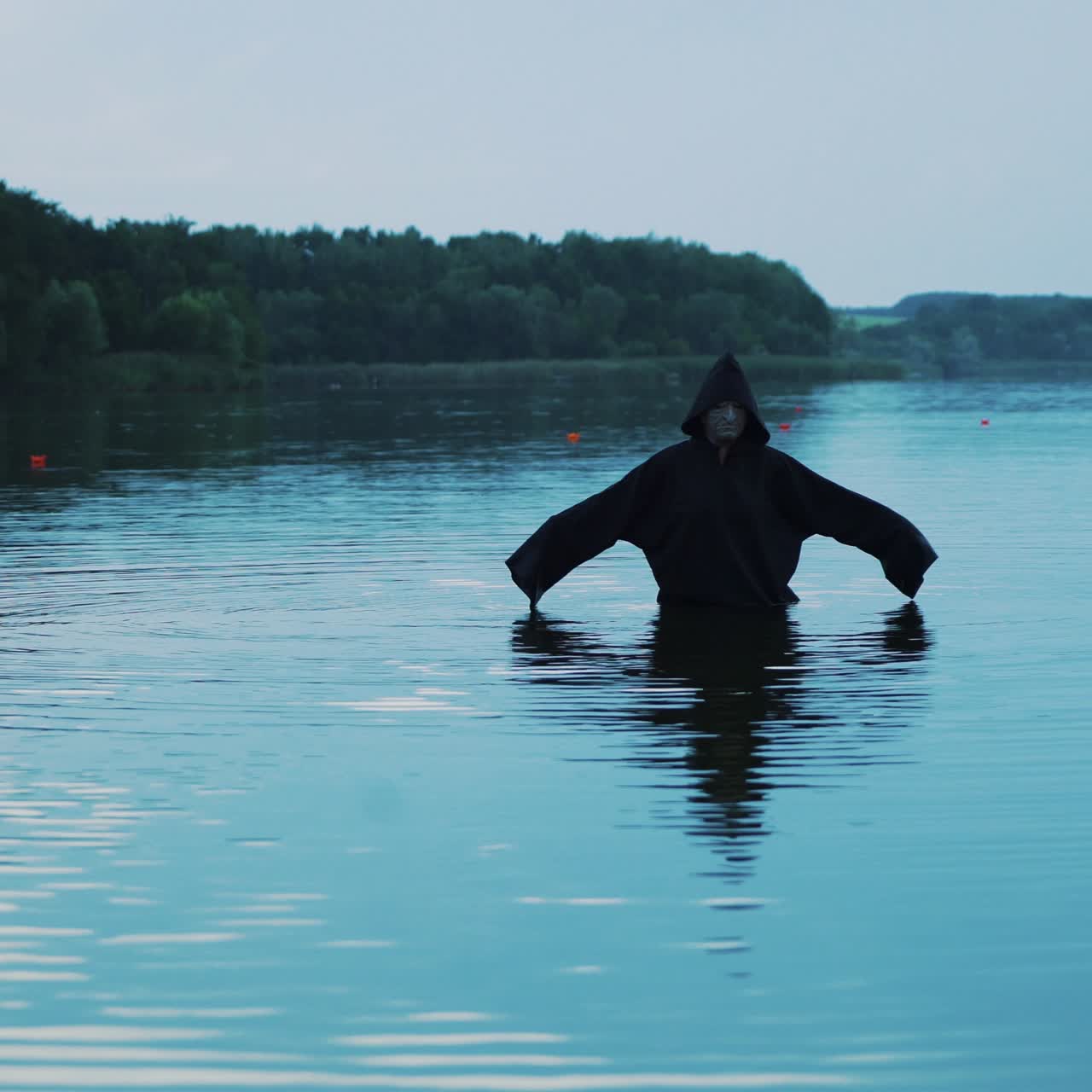 Evil witch in black cloak with hood in the river. Halloween costume.