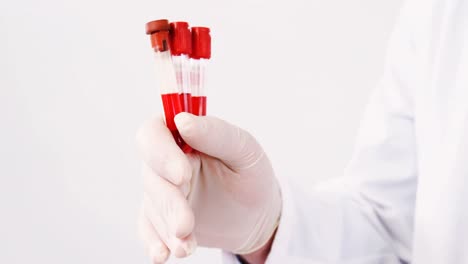 mid section of lab technician holding blood sample in tube