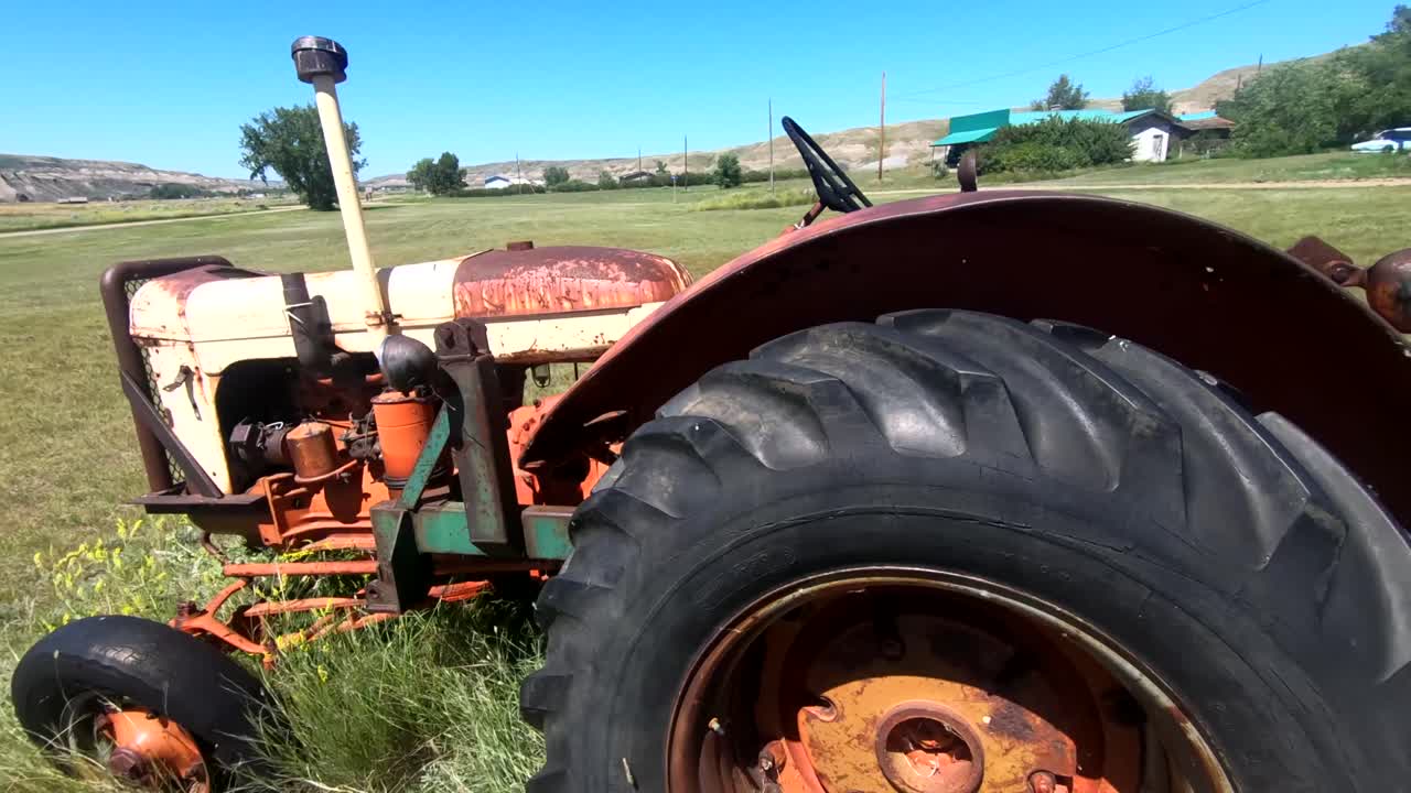 캐나다 앨버타 근처 농장의 시골 들판에 있는 풀밭에 앉아 있는 오래된 빨간 녹슨 트랙터