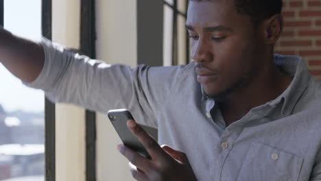 Attraktiver-Afroamerikanischer-Mann,-Der-Zu-Hause-Ein-Smartphone-Benutzt-Und-Kaffee-Trinkt,-Genießt-Entspannten-Morgen-Das-Durchsuchen-Von-Nachrichten,-Das-Vernetzen-Von-SMS-Und-Das-Teilen-Seines-Lebensstils-Online-Aus-Nächster-Nähe