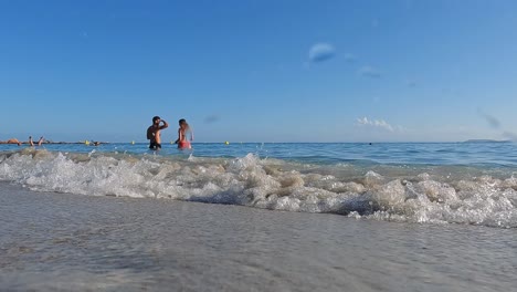 Vista-De-La-Superficie-De-Arena-De-ángulo-Bajo-De-Una-Pareja-Relajándose-En-El-Agua-De-Mar-De-La-Famosa-Playa-De-Palombaggia-En-Córcega,-Francia