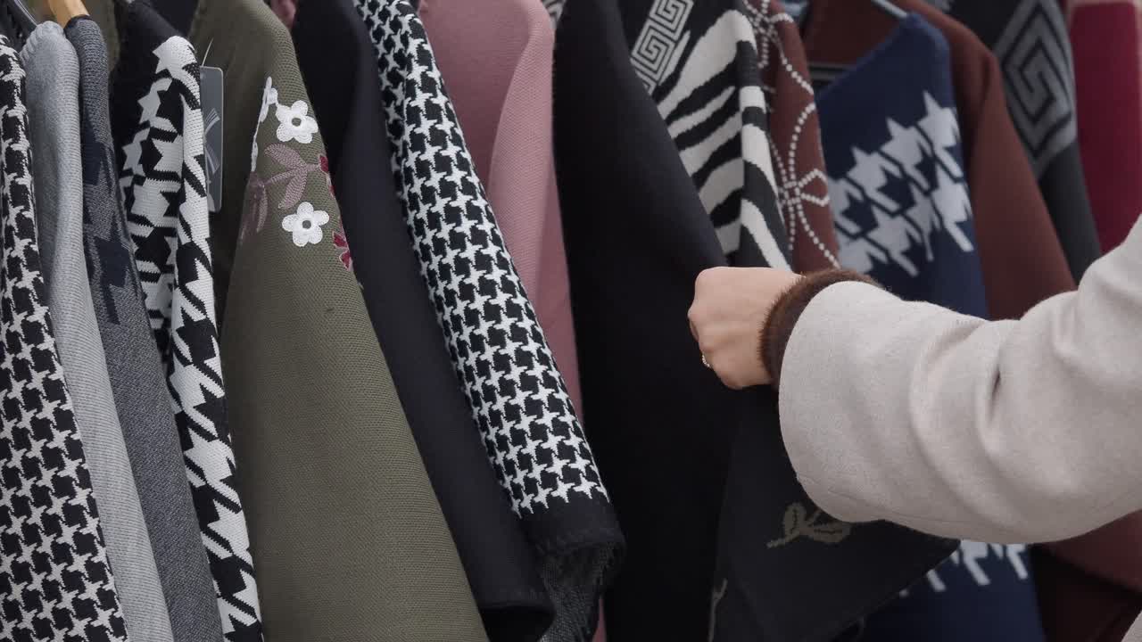 Woman's Hand Browsing Through Clothes on a Hanger Rack
