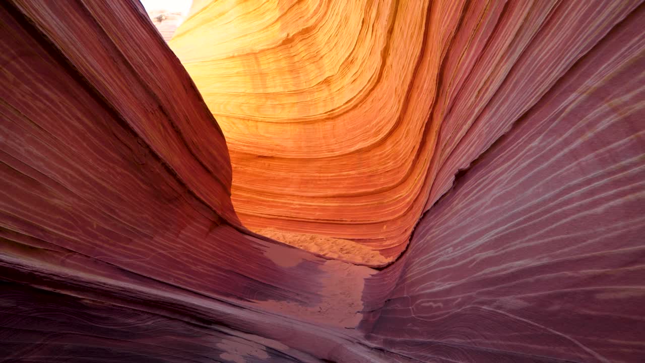 Camera gliding through The Wave sandstone structure in Arizona desert. Delicate sandstone carved by thousands of years of wind erosion. Unique geological formation and hiking trail near Knab Utah.