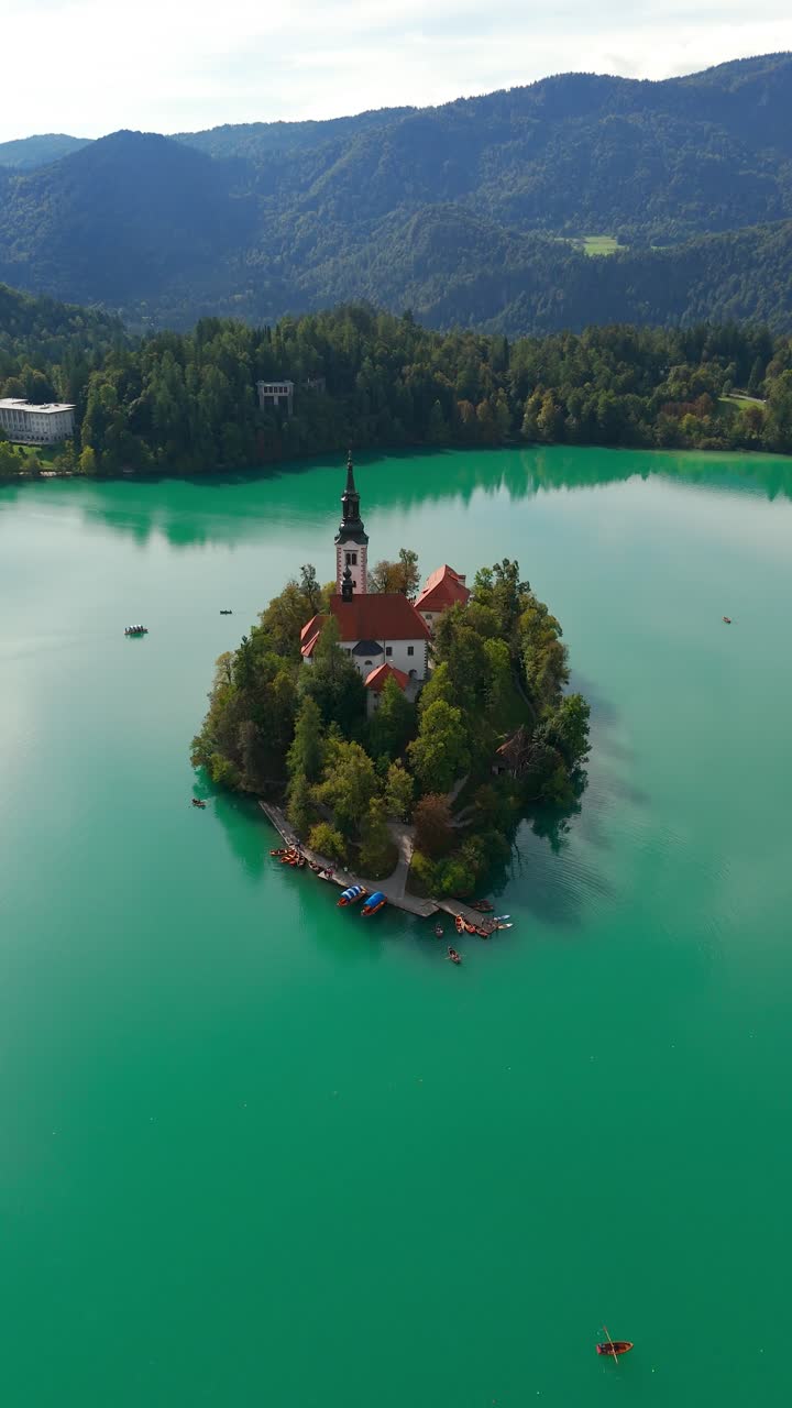 Vertical drone fly over Bled Island and church of the Assumption of St. Mary, Julian Alps, Bled, Slovenia
