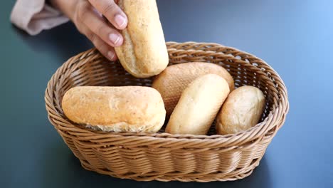 hand reaching into a basket of assorted bread rolls