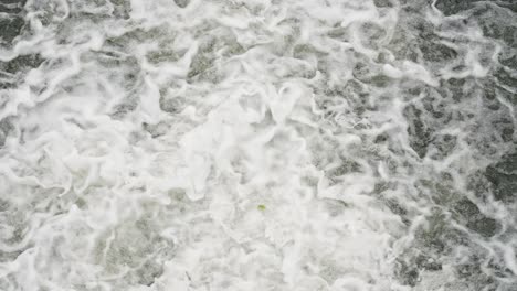 flowing stream on the river dam splashing out from the gateway with foamy waves. tilt-up shot