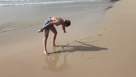 woman drawing in the sand on the beach