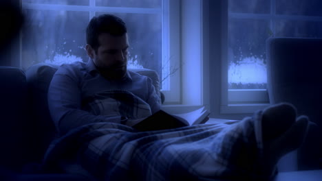 man on couch reading book in moonlight