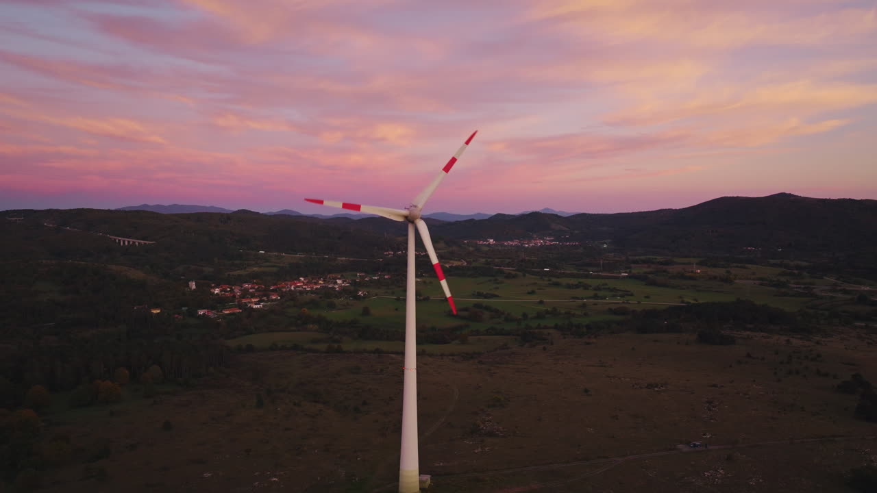 Le turbine eoliche girano su una collina durante il tramonto, evidenziando l'uso dell'energia rinnovabile per la produzione di elettricità