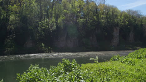 Toma-Lateral-Extra-Ancha-Al-Sur-Del-Estanque-Del-Lago-Y-Garganta-De-Piedra-Caliza-Con-Vegetación-En-Primer-Plano-En-Creswell-Crags