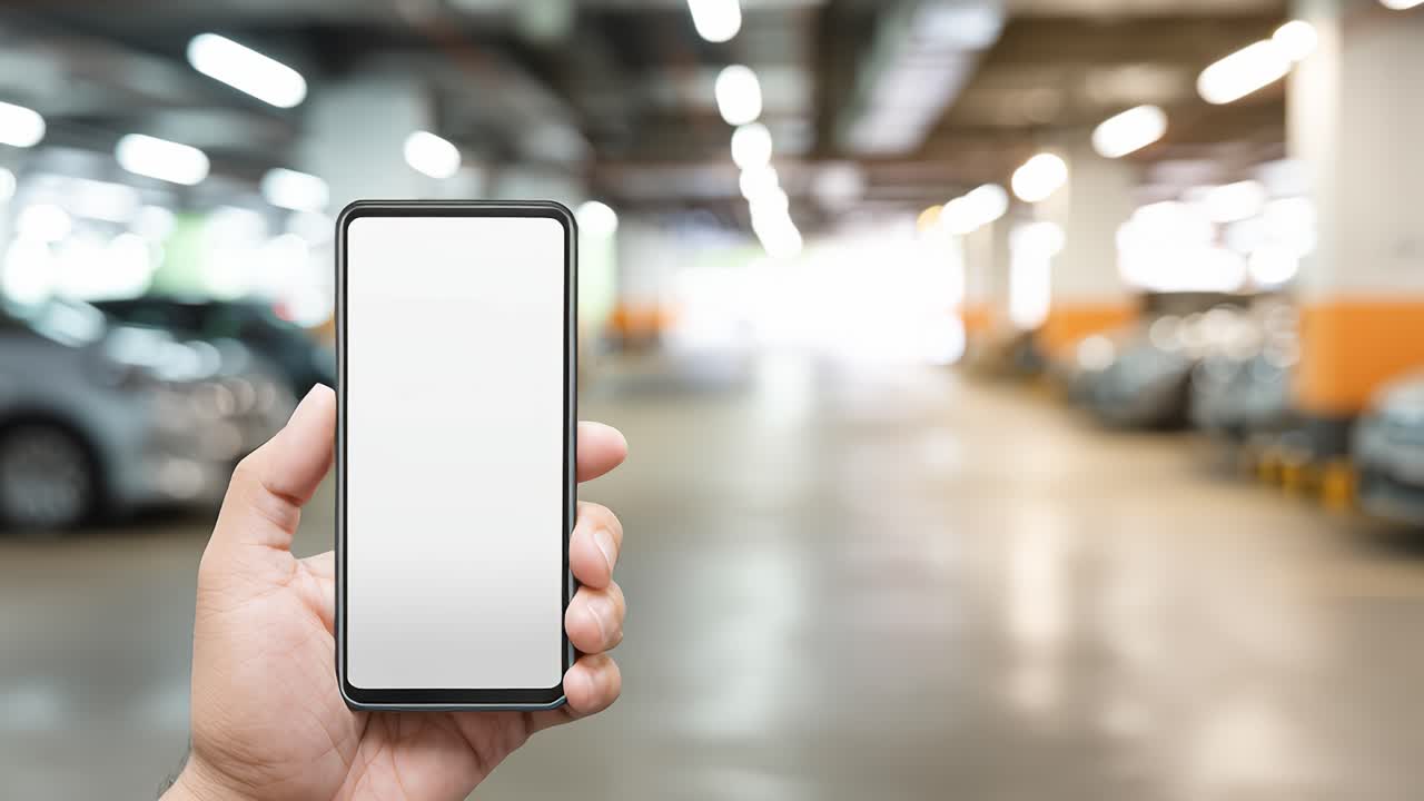 Hand holding smartphone with white screen in parking lot