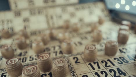 Macro-video-of-a-Bingo-board,-studio-lights,-120-fps,-slow-motion,-wooden-chip-digits,-Raw-footage,-lottery-desk-game,-card-numbers