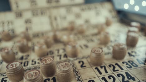 video macro de un tablero de bingo, luces de estudio, 120 fps, cámara lenta, dígitos de chips de madera, imágenes en bruto, juego de mesa de lotería, números de cartas