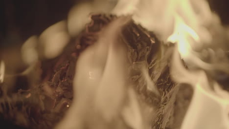 slowmotion shot of a fire and flames burning away a newspaper in a fire pit creating sparks and smoke log
