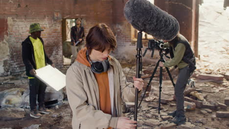 woman production worker setting up the microphone and the looks at the camera