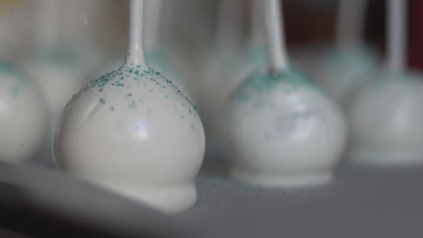 close up of white cake pops, edible pastry glitter falling on them, slow motion 120fps