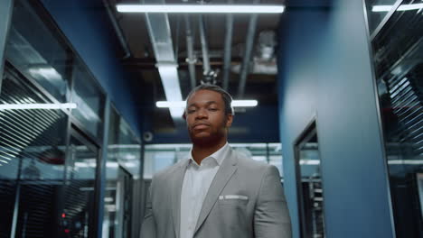 african american man staring at lens in corridor. businessman waiting for meetup