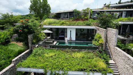 aerial-drone-of-a-young-caucasian-model-walking-in-front-of-any-infinity-pool-at-a-private-luxury-white-villa-at-a-hotel-and-resort-on-a-sunny-summer-day-in-Bali-Indonesia