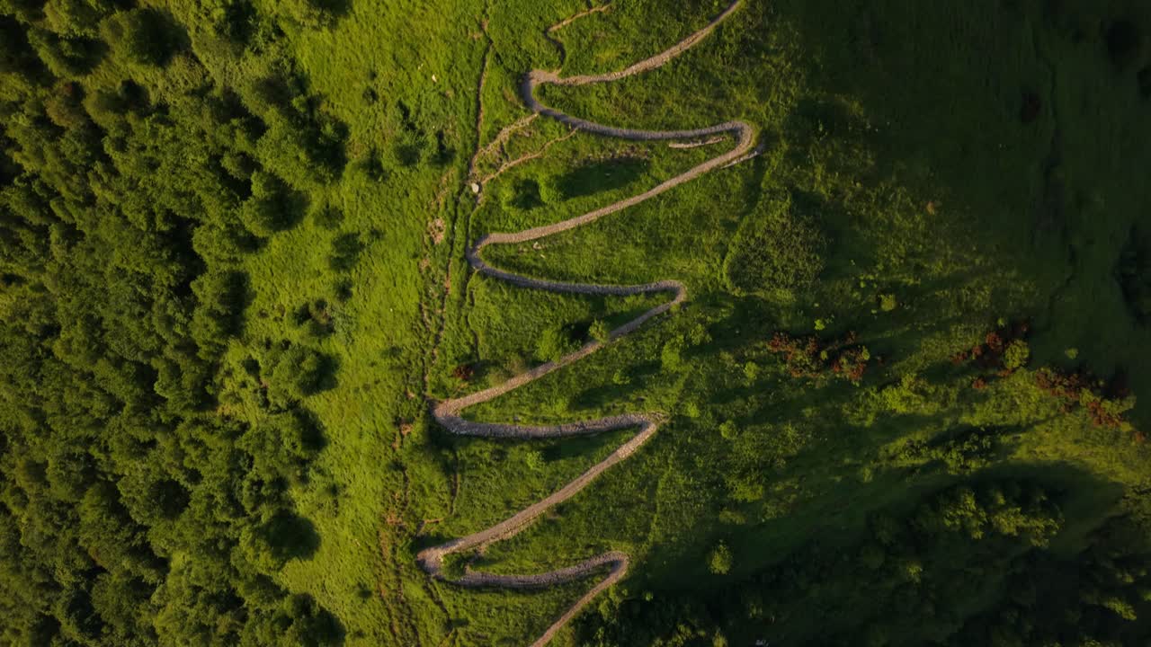 Ancient fort in Italy with winding paths, trees, and people running on grassy terrain