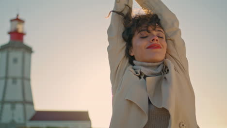 fashionable girl walking sunlight at lighthouse. serene happy woman closing eyes