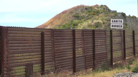 the us mexico border wall fence with a sign saying border in background 1