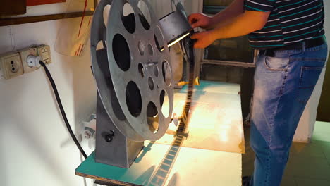 movie technician puts film reel on spool to show old picture
