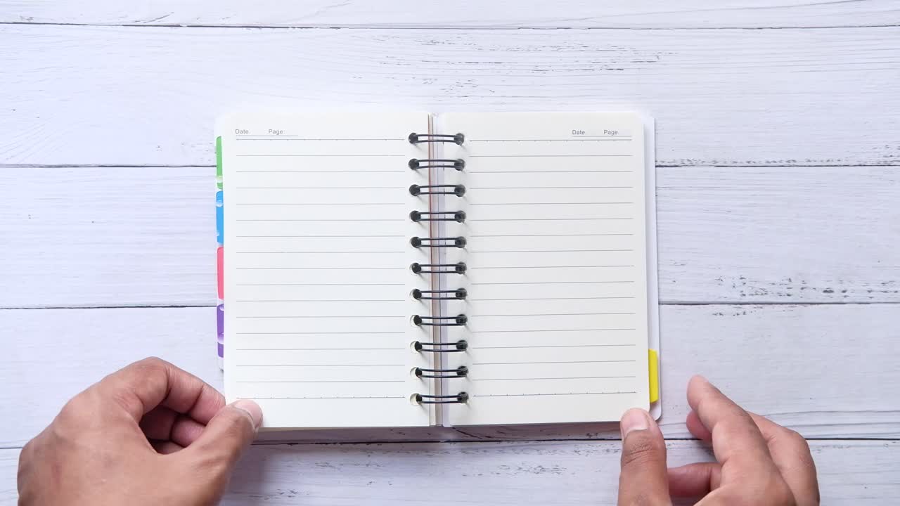 Hands opening a spiral-bound notebook