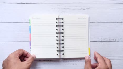 hands opening a spiral-bound notebook