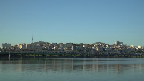 Seoul-Skyline-from-Han-river-Park-Waterfront-with-N-Seoul-Tower-and-Yongsan-district-over-clear-blue-sky,-Traffic-on-Gangbyeon-Expressway---copy-space