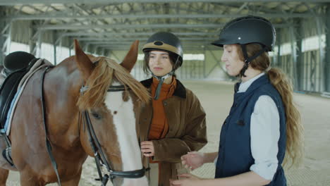 woman stroking horse and talking with female instructor